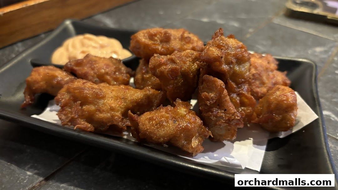 A plate of crispy fried chicken bites served with a side of dipping sauce.