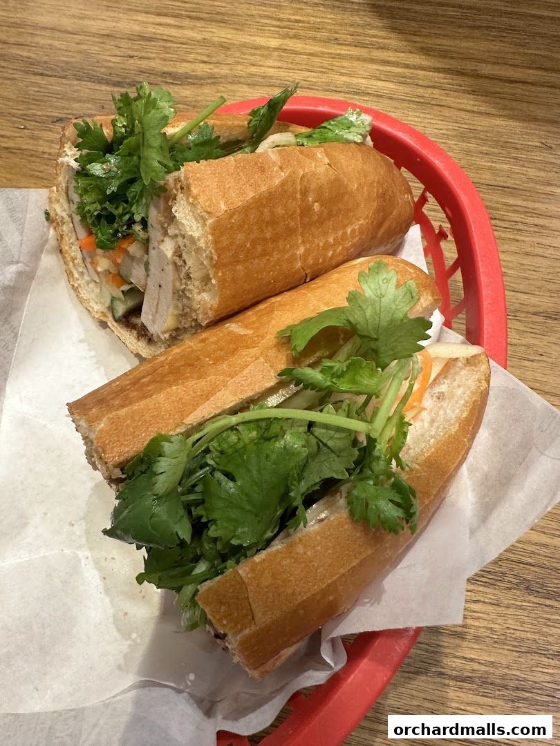 Two delicious banh mi sandwiches filled with fresh ingredients in a red basket.
