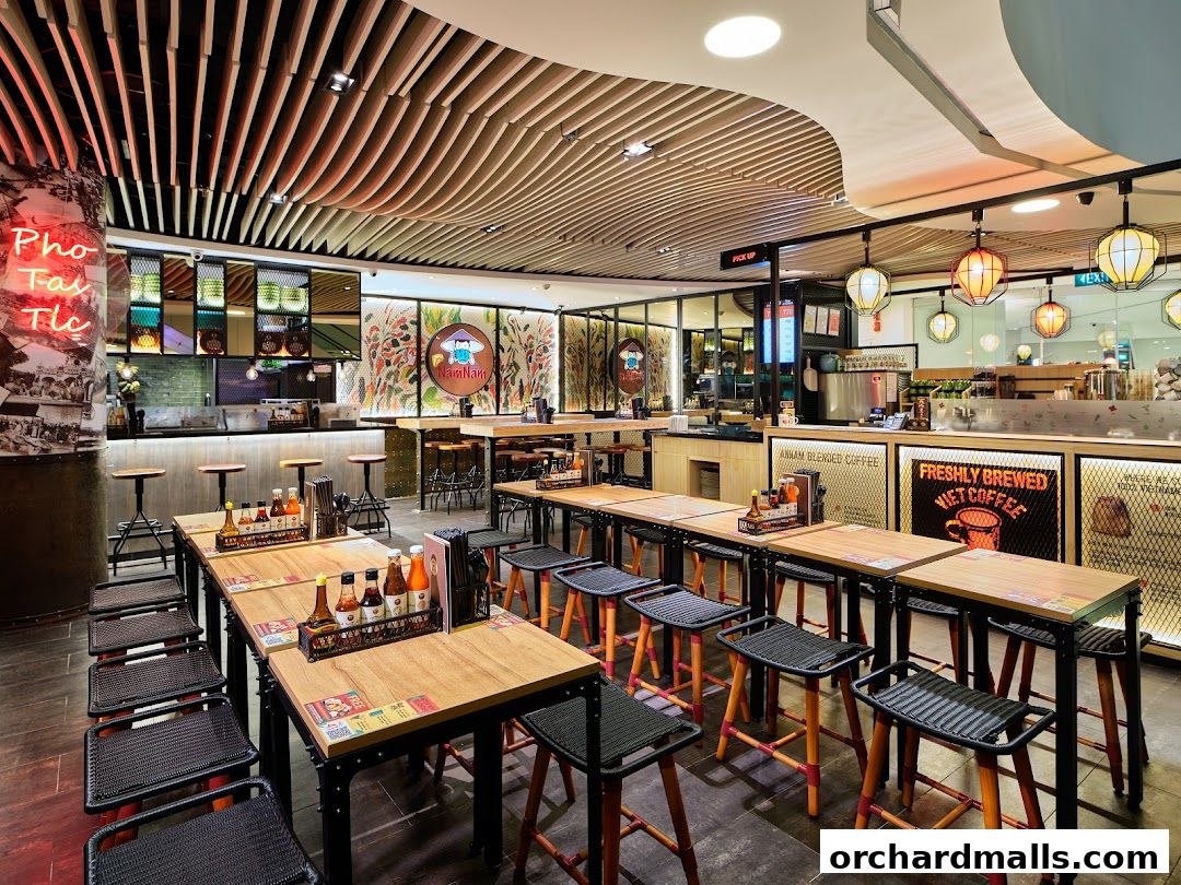 Interior of NamNam Wheelock Place, showing dining tables, stools, and counter area.
