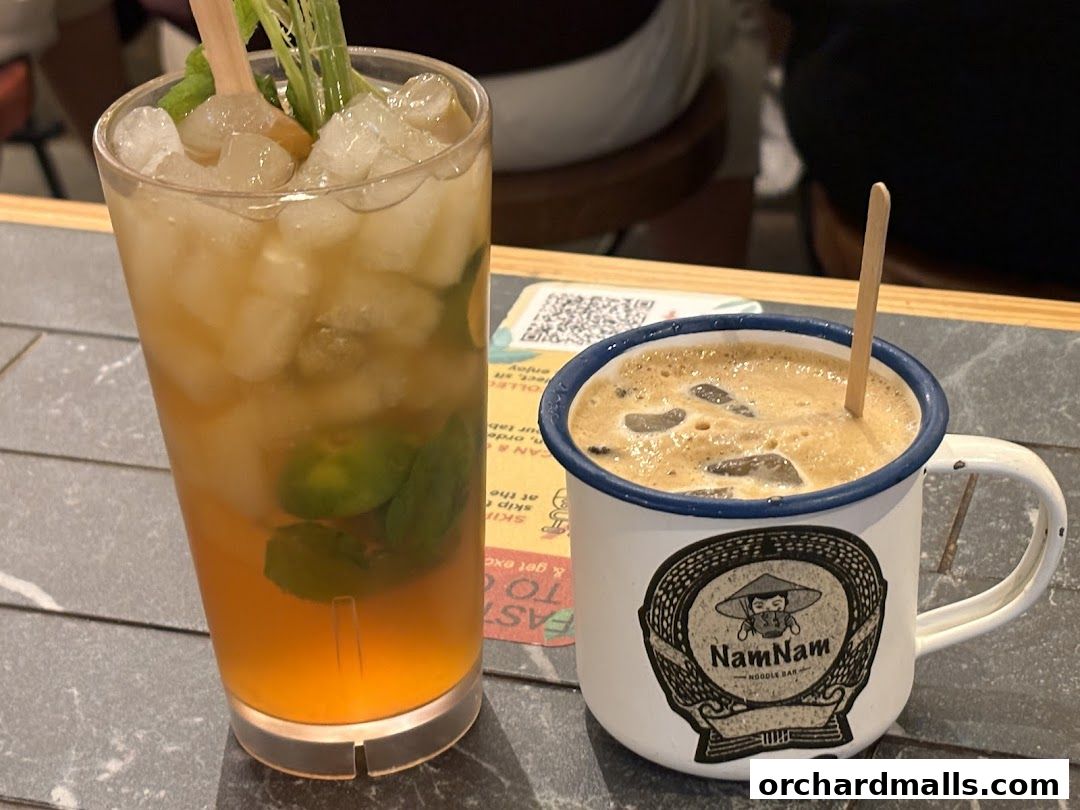 A refreshing iced drink and a coffee in a mug with the NamNam Noodle Bar logo.