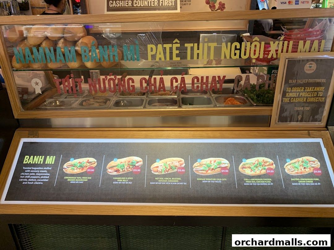 A display case with banh mi ingredients and a menu board showing various sandwich options.