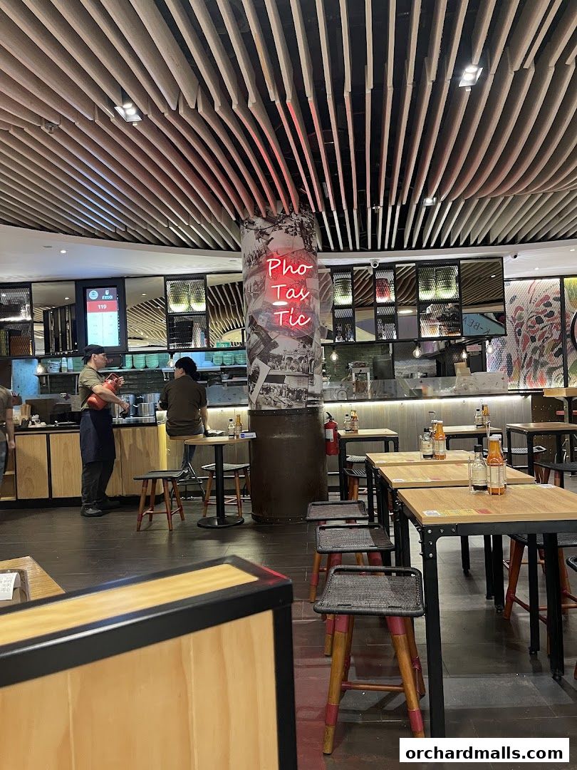 Interior of a modern Vietnamese restaurant with tables, chairs, and a neon sign.