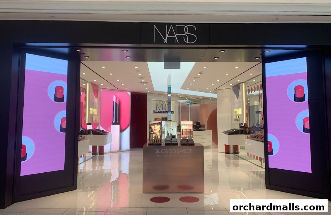 The entrance of a NARS cosmetics store with digital displays showcasing lipstick.
