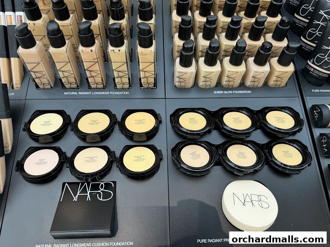 A display of NARS foundation products, including liquid and cushion foundations in various shades.