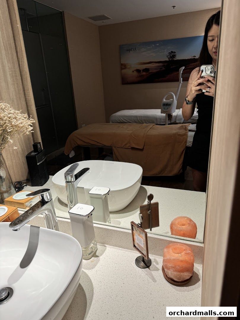 Reflection of a spa room with massage beds and a sink area.