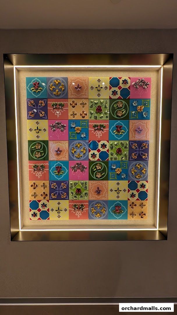 A framed display of colorful tiles with floral motifs and metallic accents.