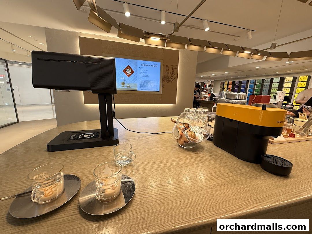 Nespresso boutique interior with coffee machines, capsules, and tasting cups on a wooden counter.