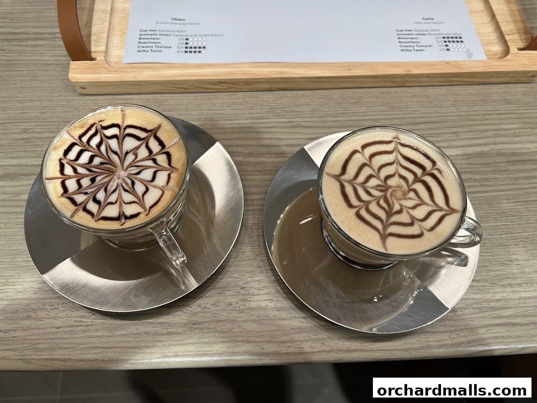 Two cups of coffee with latte art on a wooden table.