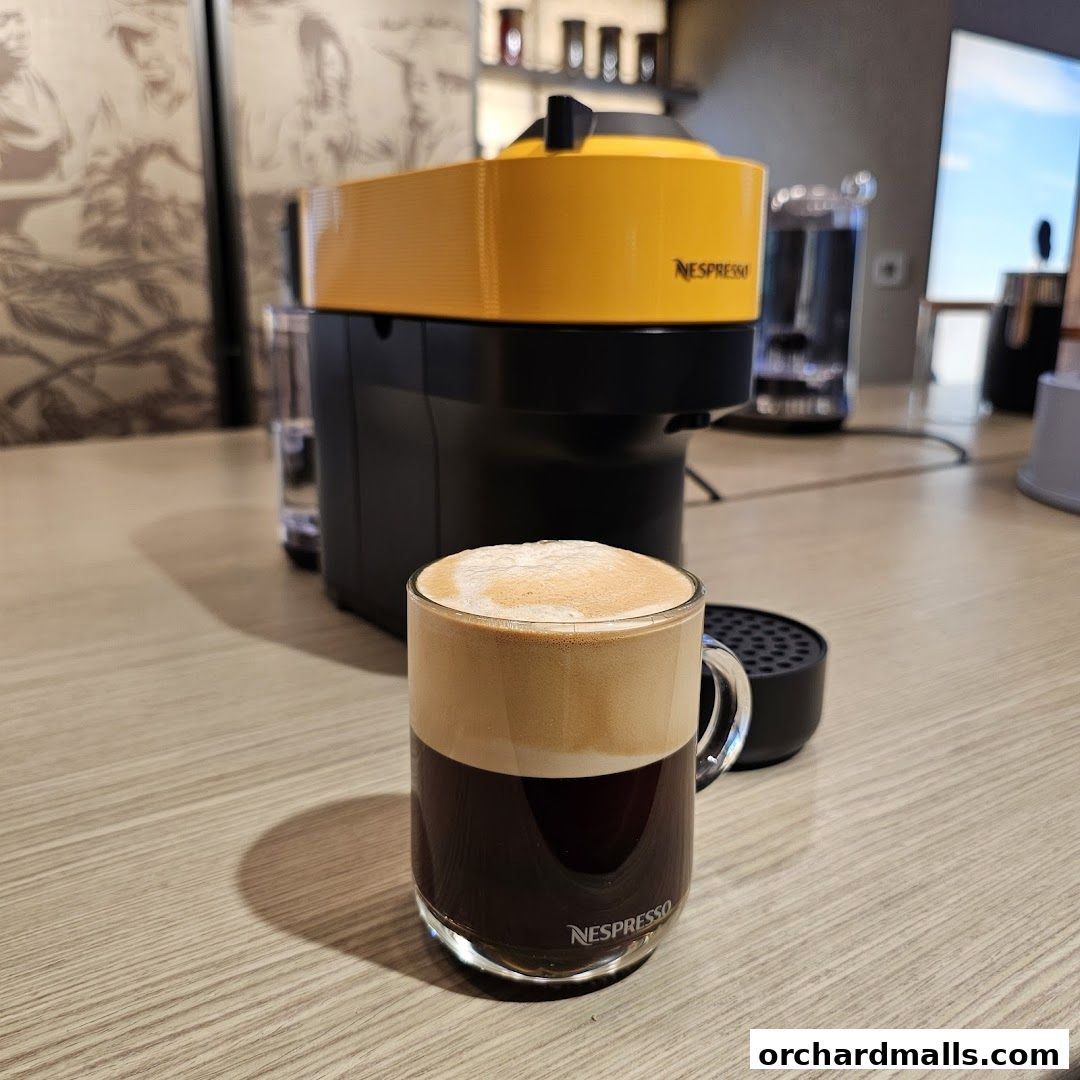 A Nespresso coffee machine with a freshly brewed coffee in a glass mug.