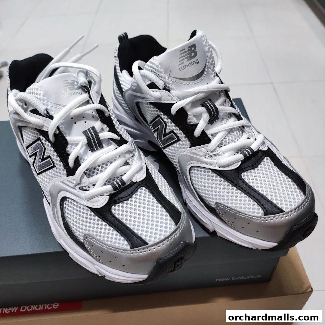 A pair of white and silver New Balance running shoes with black accents.