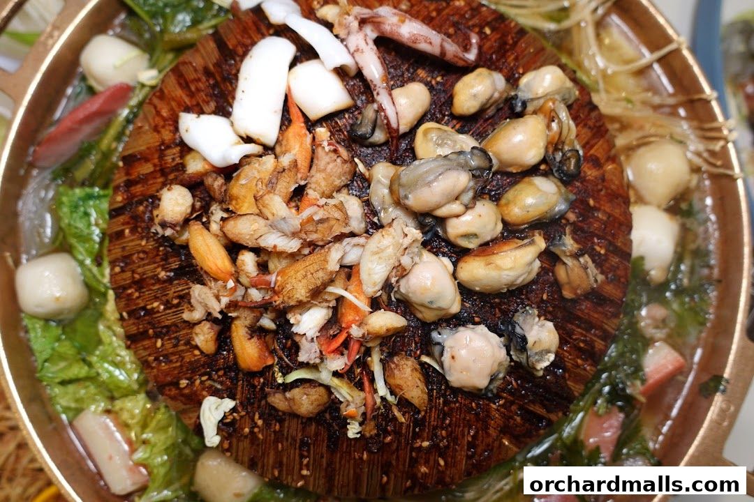 A close-up of a Mookata pot filled with seafood, vegetables, and meatballs.