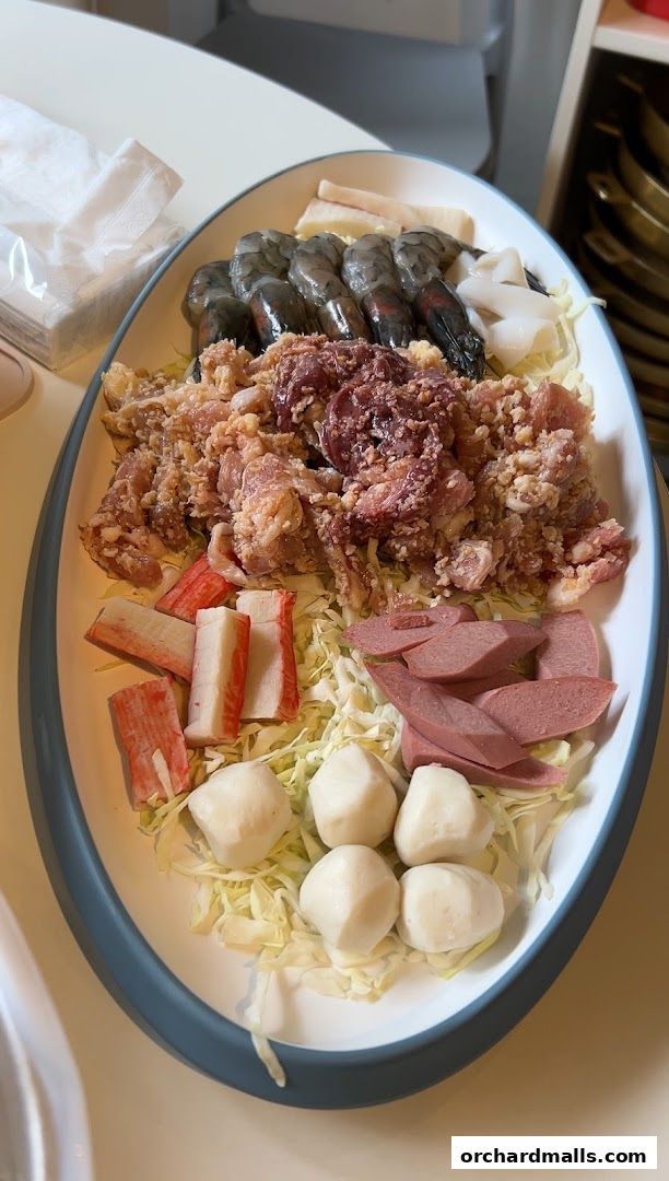 A platter of raw ingredients for Mookata, including shrimp, meat, meatballs, and vegetables.