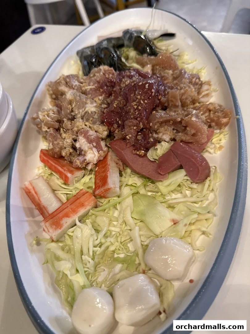 A platter of raw ingredients for Mookata, including meats, seafood, and vegetables.