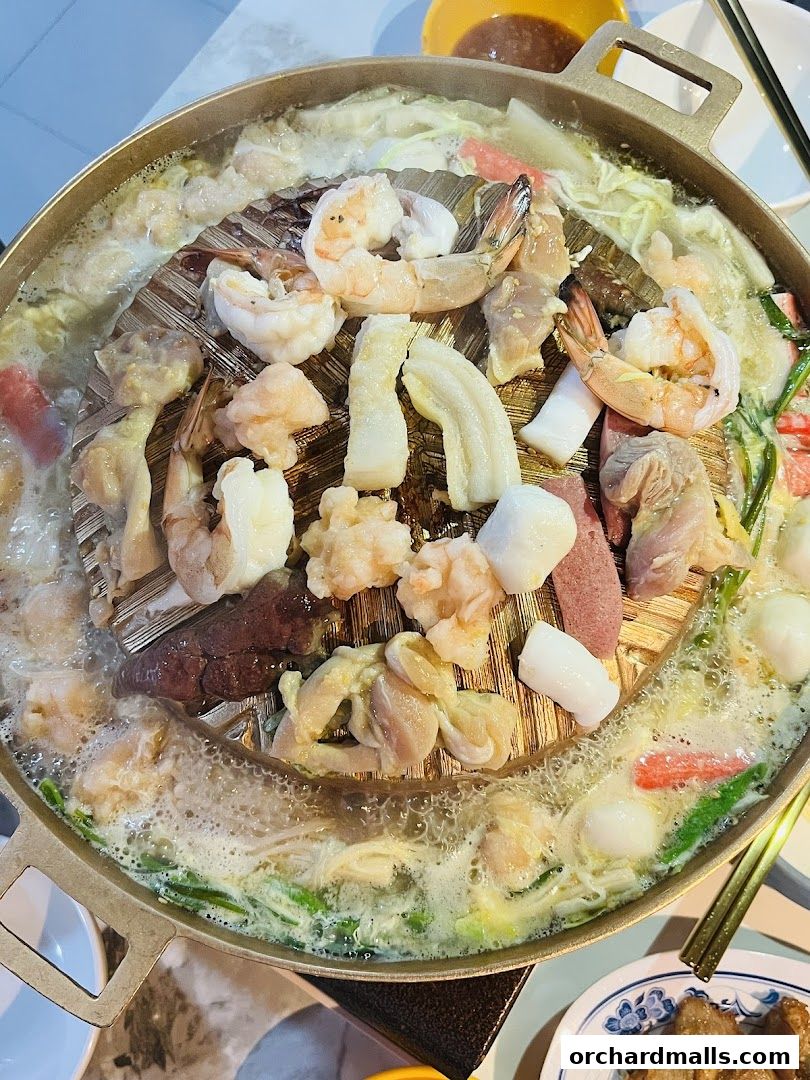 A close-up of a Mookata hot pot filled with various meats, seafood, and vegetables.