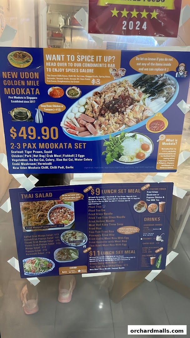 A menu board for New Udon Golden Mile Mookata Thai Food, featuring sets and salads.