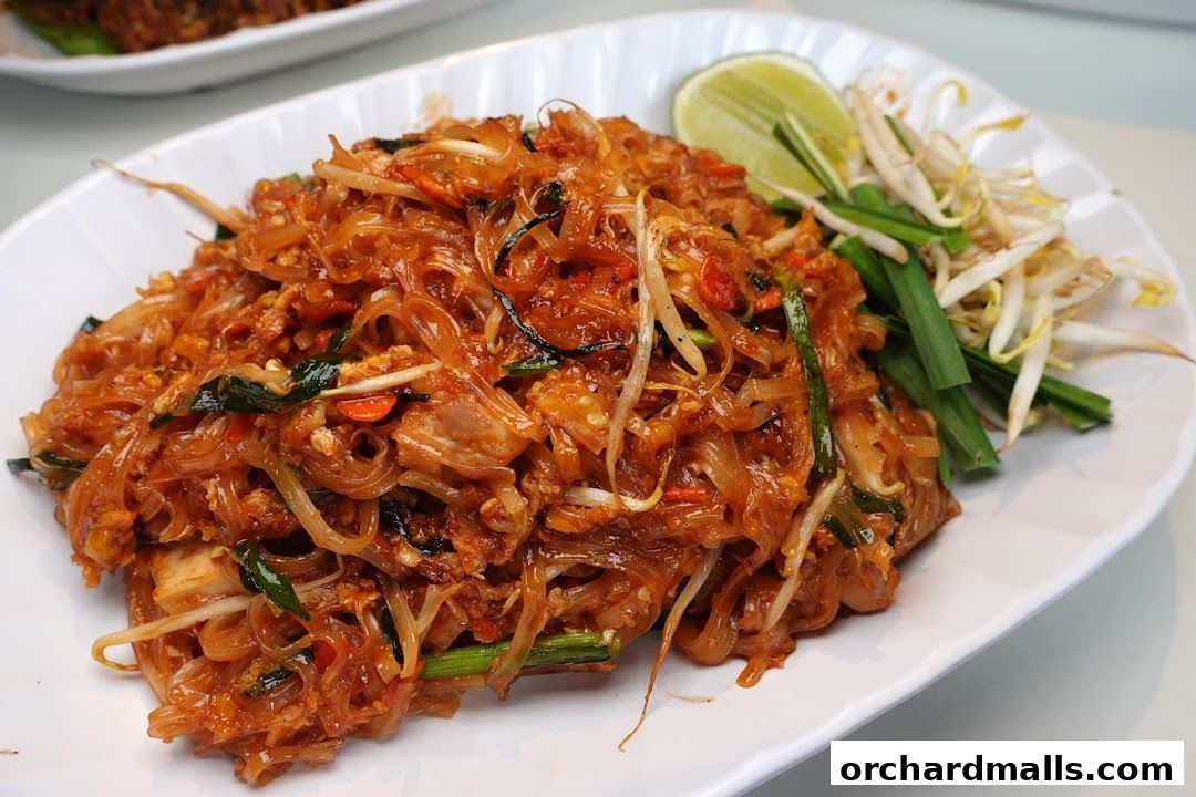A close-up shot of a delicious plate of Pad Thai noodles with lime and bean sprouts.