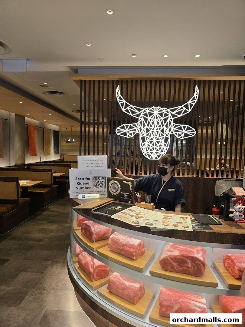 A restaurant interior with a display of raw meat cuts and a staff member at the counter.