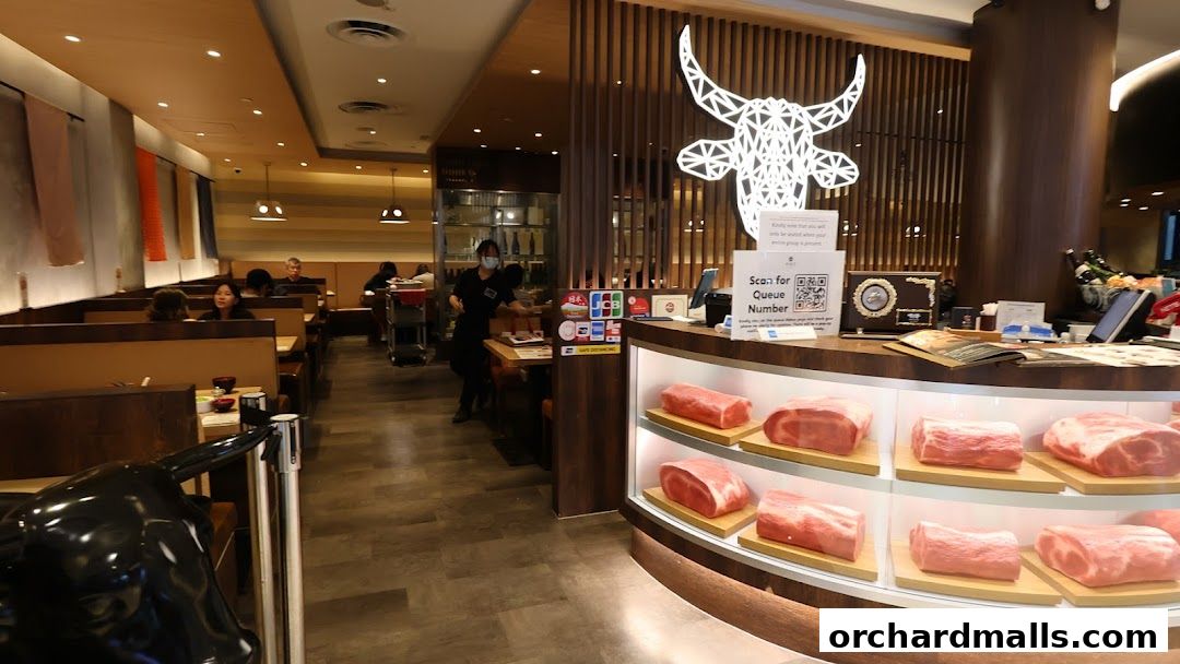 Interior of a restaurant with raw meat displayed and customers seated at tables.