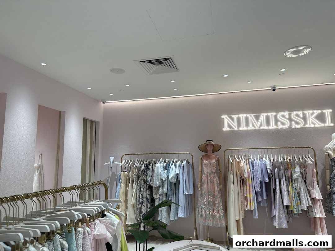 Interior view of NIMISSKI clothing store with racks of dresses and a mannequin.