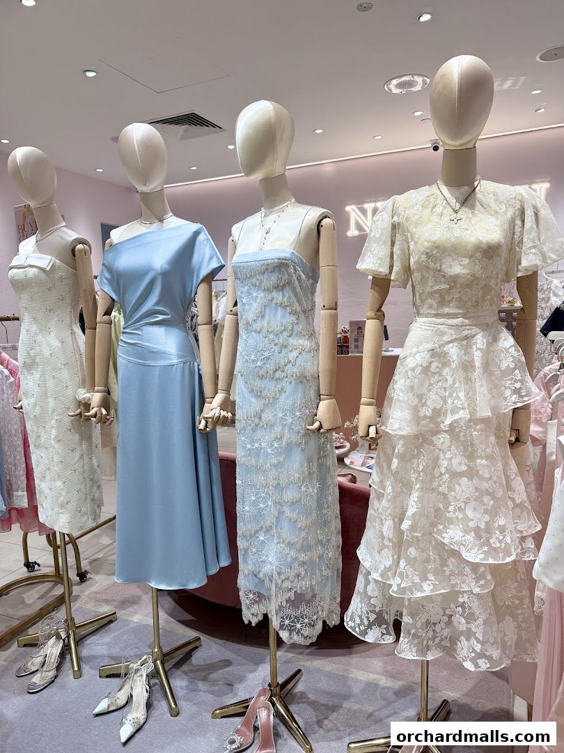 Mannequins display elegant dresses and shoes in a boutique setting.