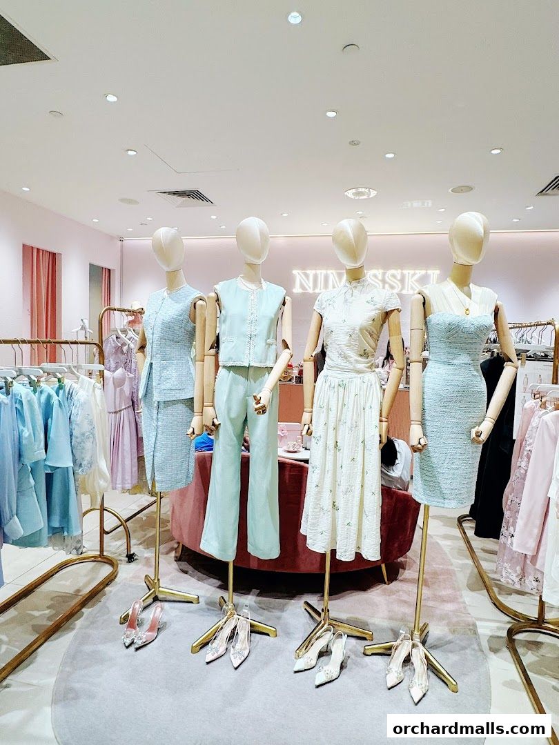 Mannequins display elegant pastel-colored outfits and shoes in a well-lit boutique.