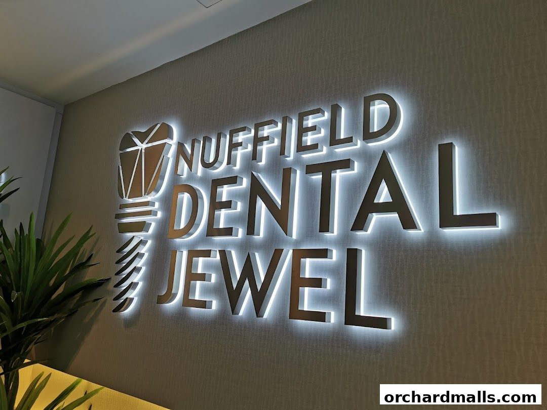 Illuminated sign for Nuffield Dental Jewel with a plant in the foreground.