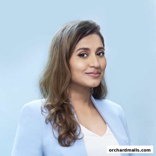 A professional portrait of a woman with brown hair wearing a light blue blazer.