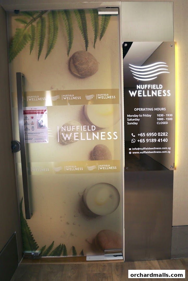 The entrance to Nuffield Wellness, featuring frosted glass with botanical elements and branding.