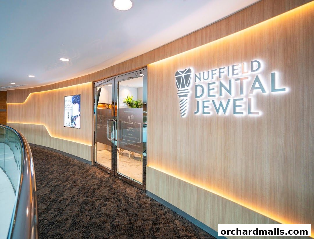 The entrance to Nuffield Dental Jewel, featuring a modern wood-paneled wall with illuminated signage.