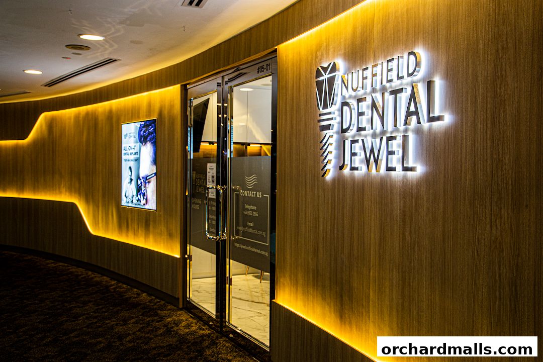 The illuminated entrance of Nuffield Dental Jewel, featuring a modern wooden facade and signage.