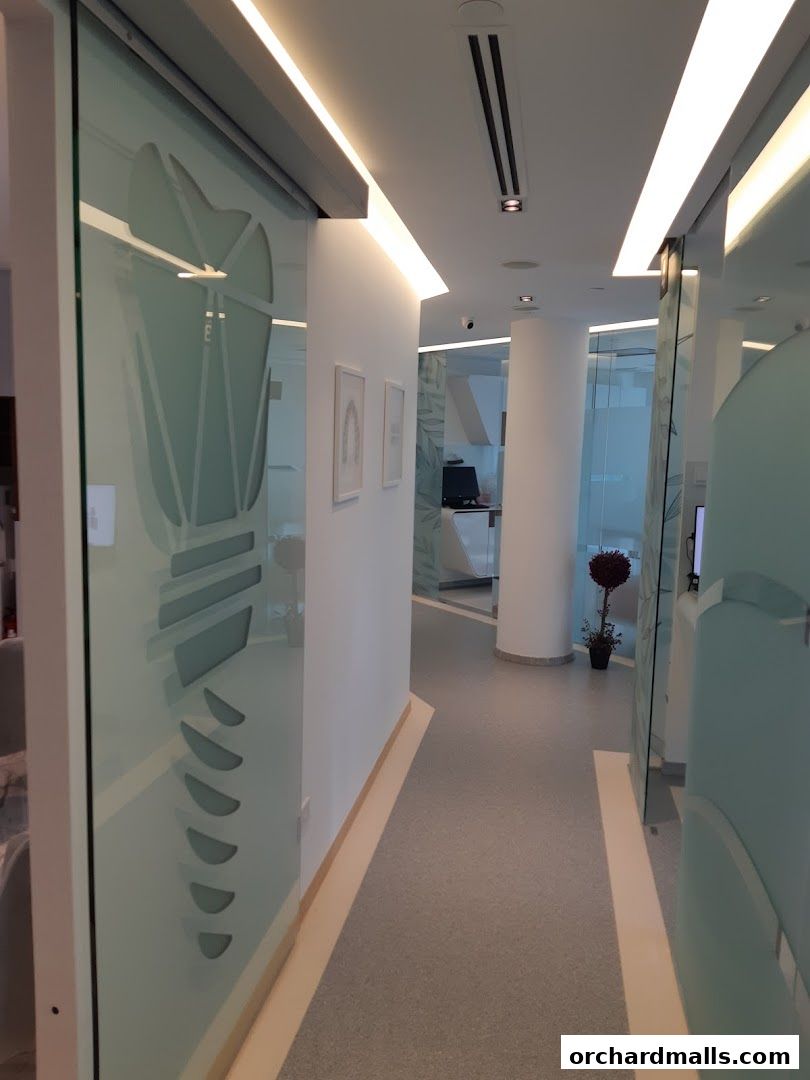 Interior hallway of a modern dental clinic with glass partitions and bright lighting.