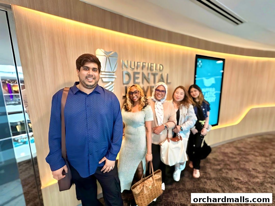 A group of people posing in front of the Nuffield Dental Jewel Wheelock logo.