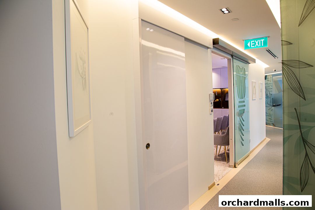 Modern clinic hallway with sliding doors, artwork, and an exit sign.
