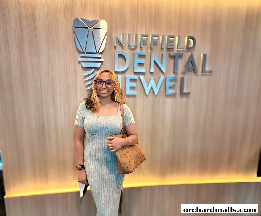 A woman stands in front of the Nuffield Dental Jewel logo and signage.