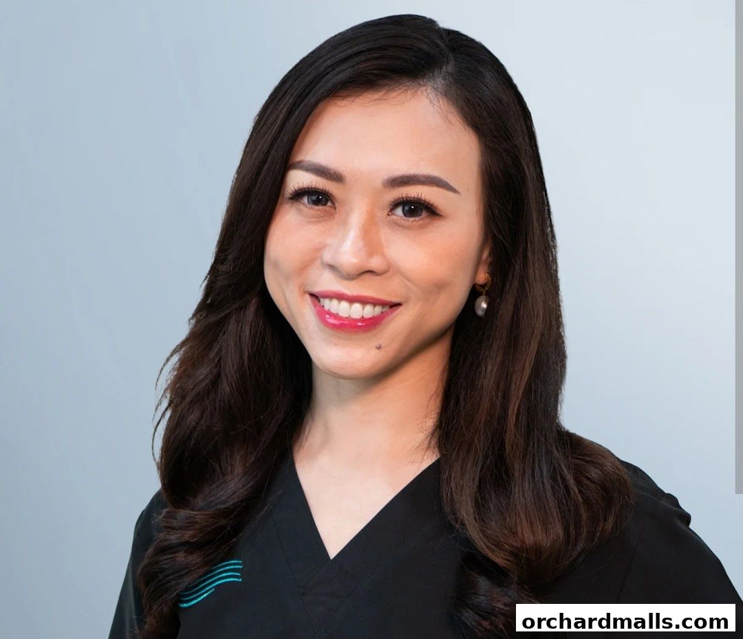 A smiling woman with long dark hair wearing a black uniform with a logo.