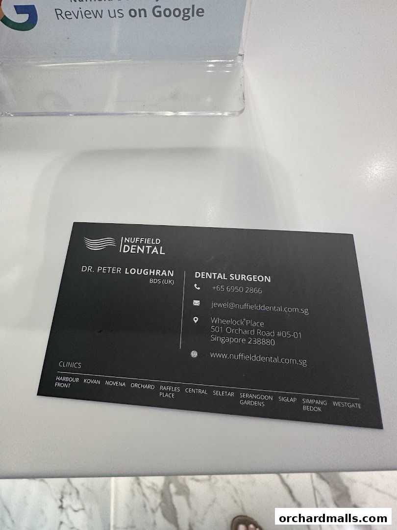 A business card for Nuffield Dental, featuring Dr. Peter Loughran and clinic locations.