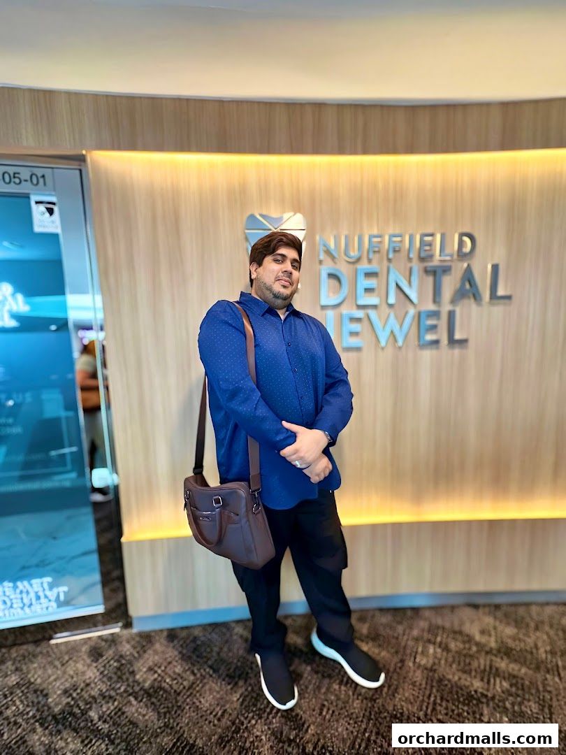 A man stands in front of the Nuffield Dental Jewel Wheelock clinic entrance.