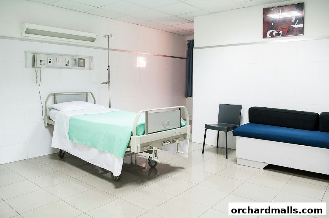 A hospital room with a bed, IV pole, and waiting chairs.