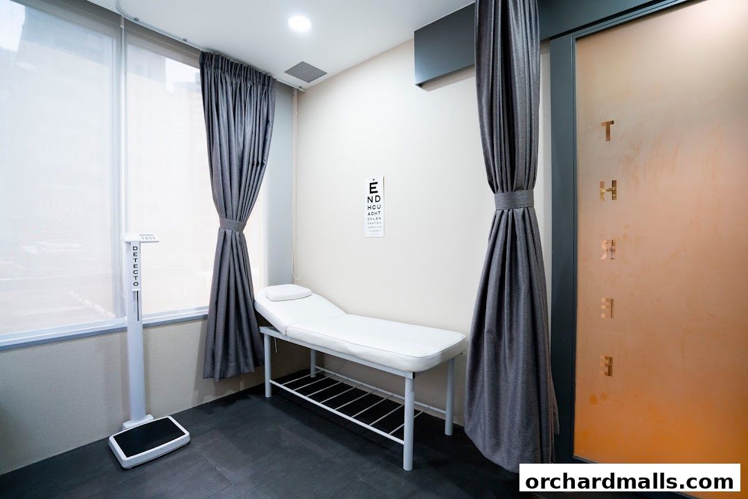 A medical examination room with a scale, examination table, and eye chart.