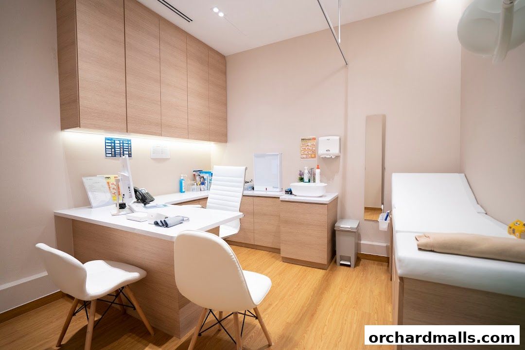 A clean and modern medical consultation room with a desk, examination bed, and medical equipment.