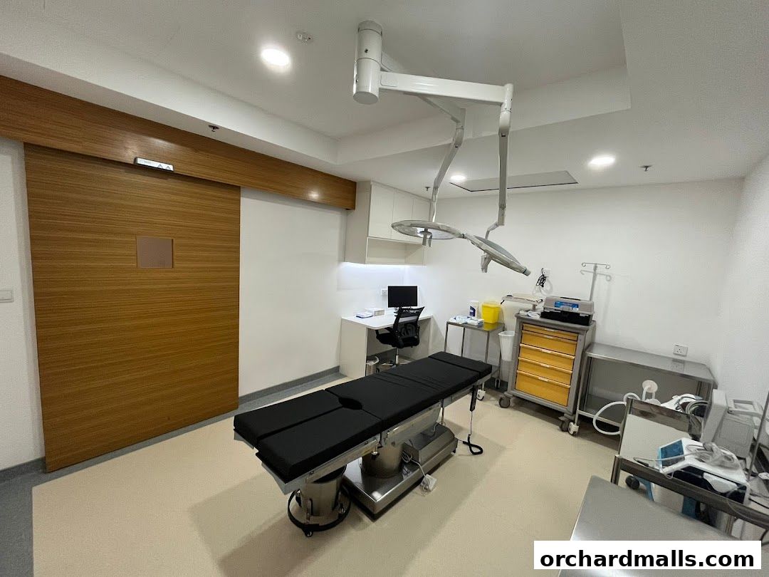 A medical examination room with a treatment bed, surgical lights, and medical equipment.