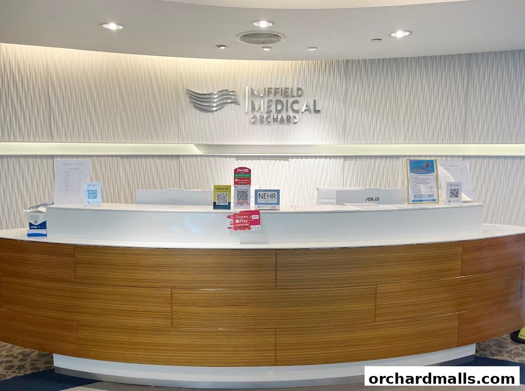 The reception counter of Nuffield Medical Orchard with the clinic's logo and various payment QR codes.