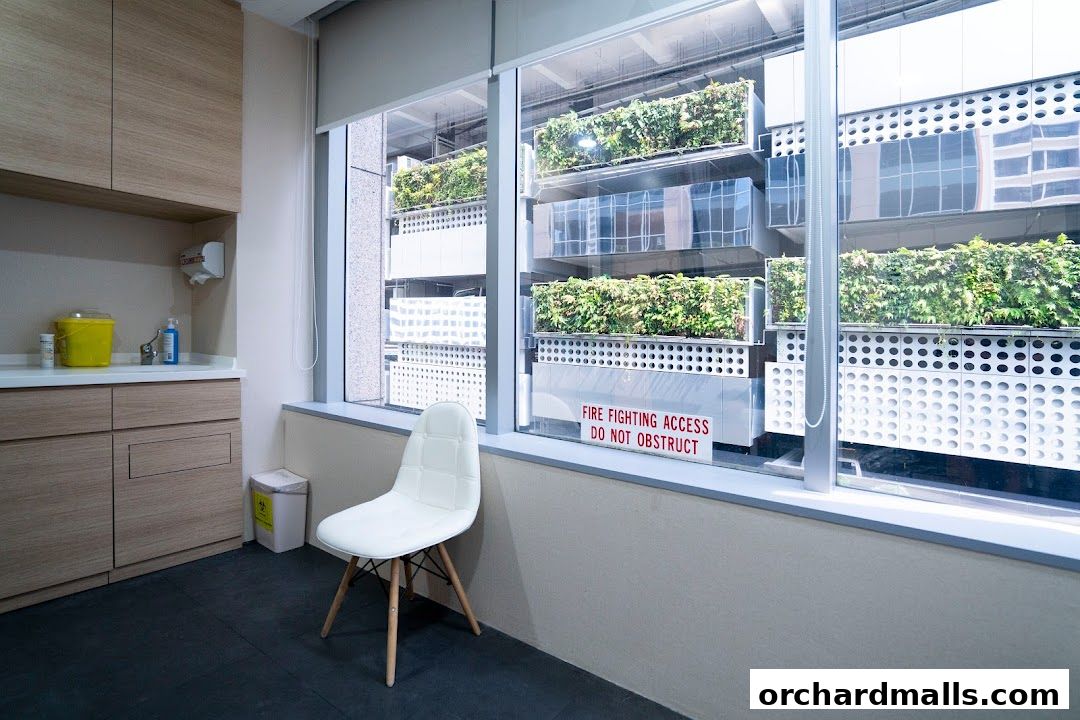 Interior of a medical clinic with a waiting chair and a view of a green facade.