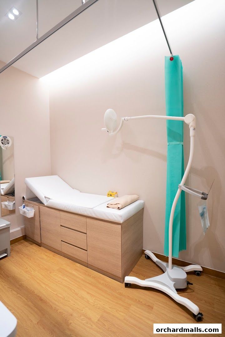 A clean and modern medical examination room with a patient bed and examination light.