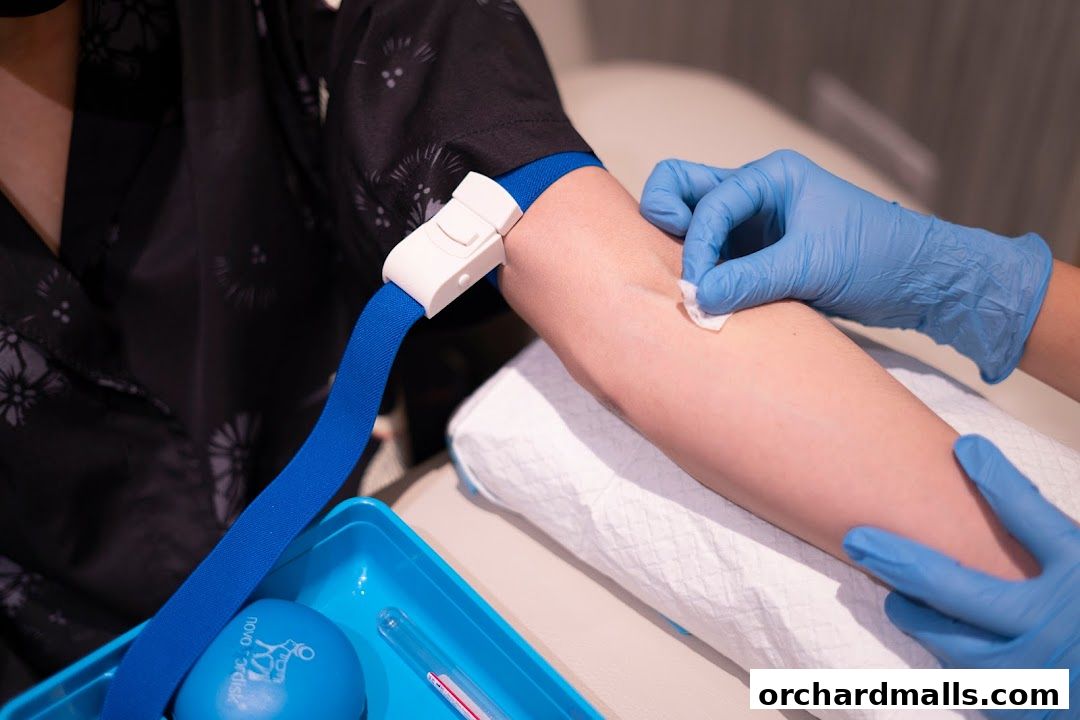 A medical professional in blue gloves prepares a patient's arm for a blood draw.