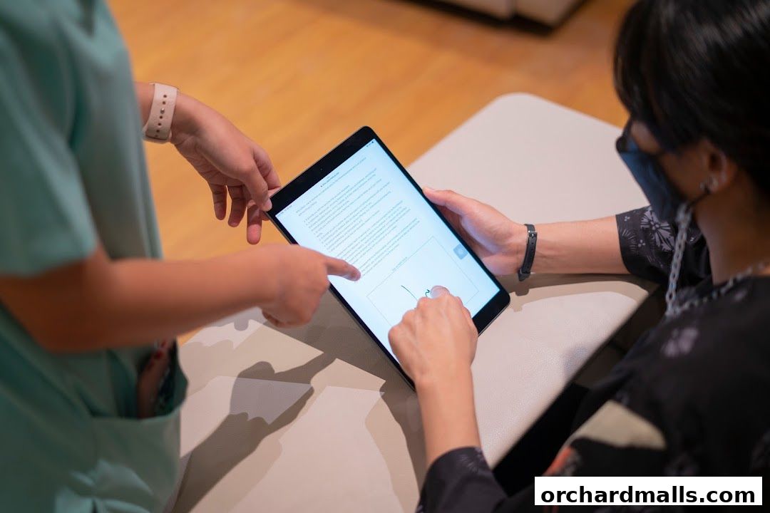 Two people are looking at a tablet, one is pointing at the screen.