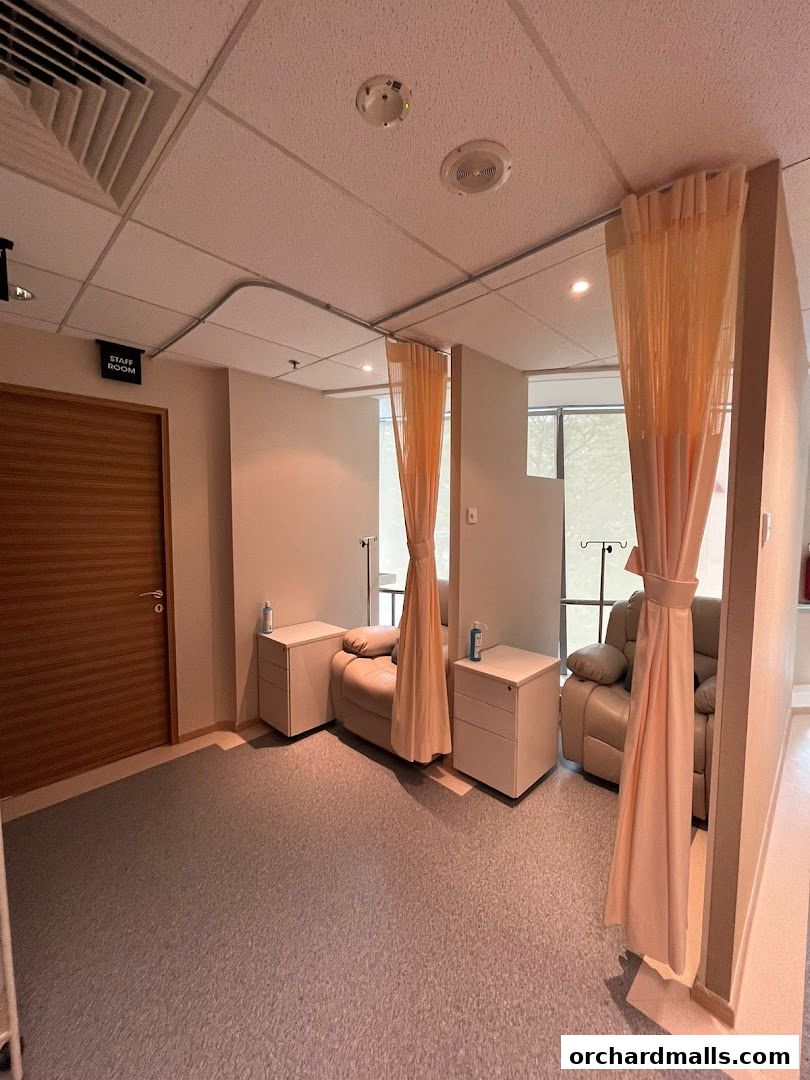 Interior view of a medical clinic's treatment room with recliners and privacy curtains.