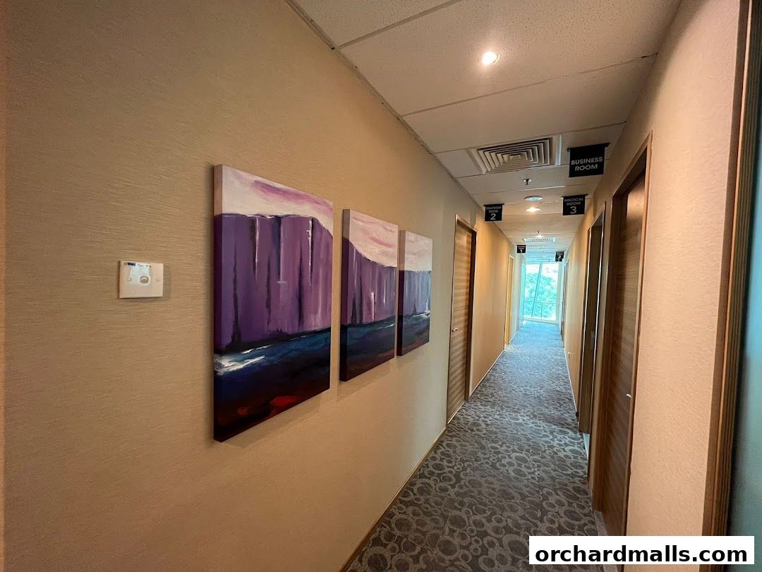 A hallway with artwork and doors leading to various rooms, including medical and business rooms.