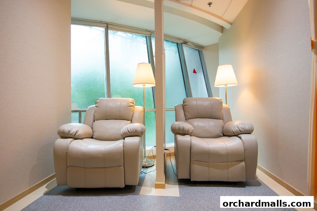 Two comfortable recliners with lamps in a waiting area with large windows.