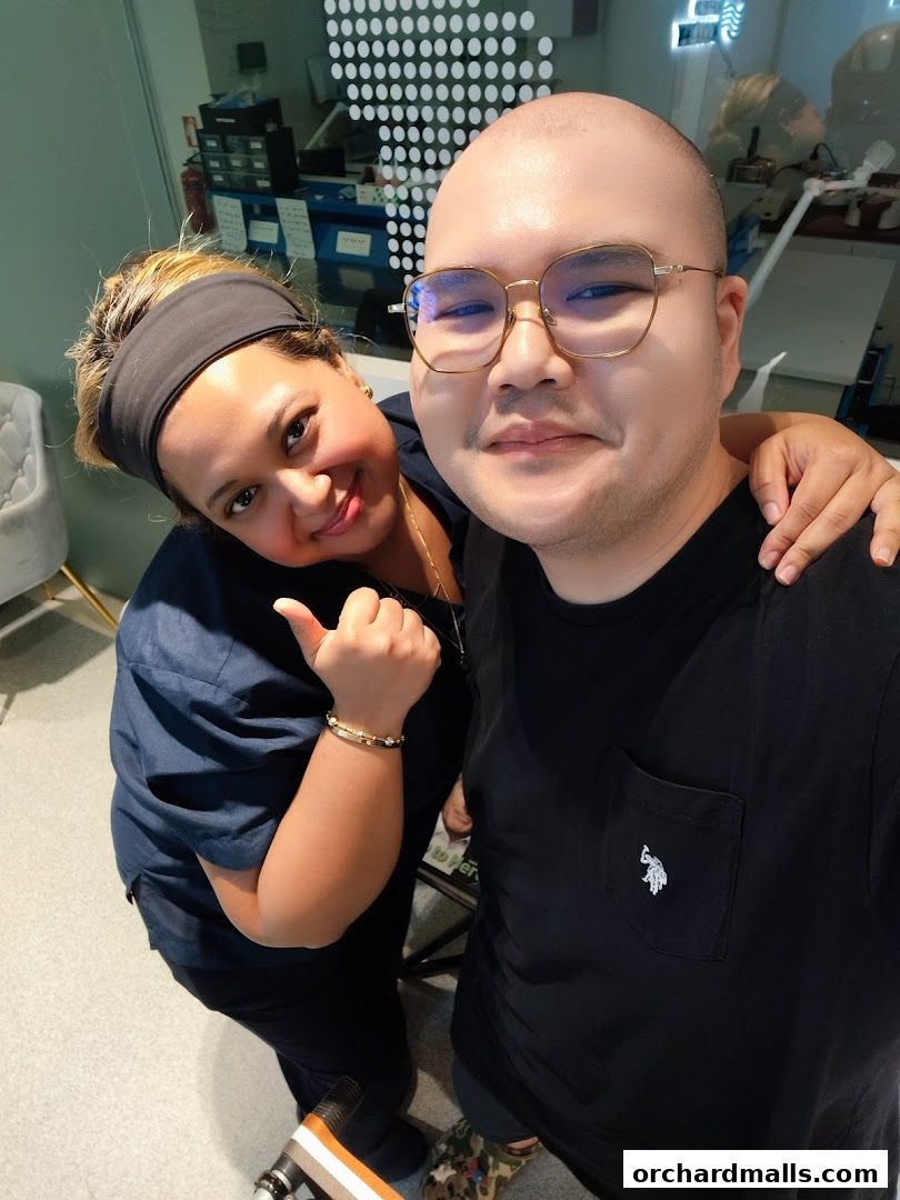 Two smiling individuals, likely staff, pose for a selfie in a clean, modern clinic setting.